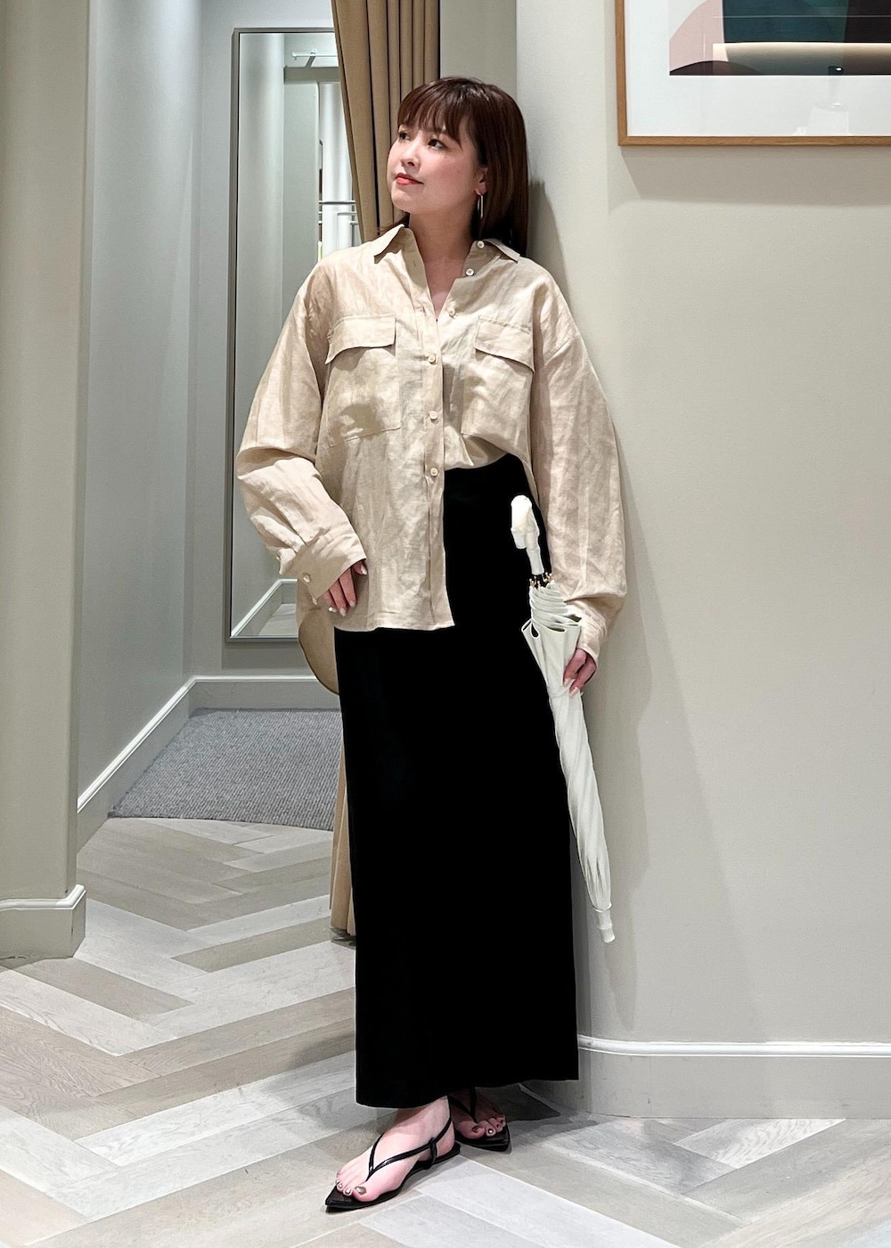 ブラック系のスカート、ベージュ系のシャツ/ブラウス、ホワイト系の長傘を着用したレディースの夏コーディネートの2枚目の写真