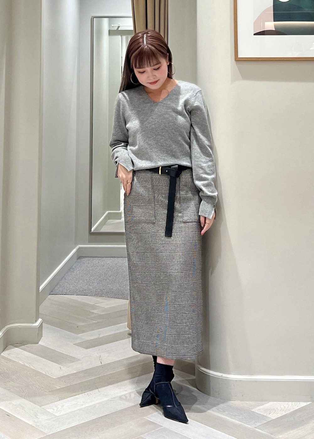 ブラック系のパンプス、ブラック系のスカート、グレー系のニット/セーターを着用したレディースの秋コーディネートの4枚目の写真