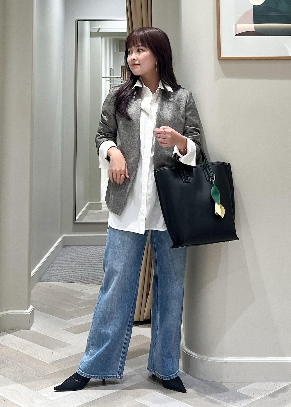 ブラック系のパンプス、ブルー系のデニムパンツ、ブラック系のトートバッグを着用したレディースの秋コーディネートの2枚目の写真