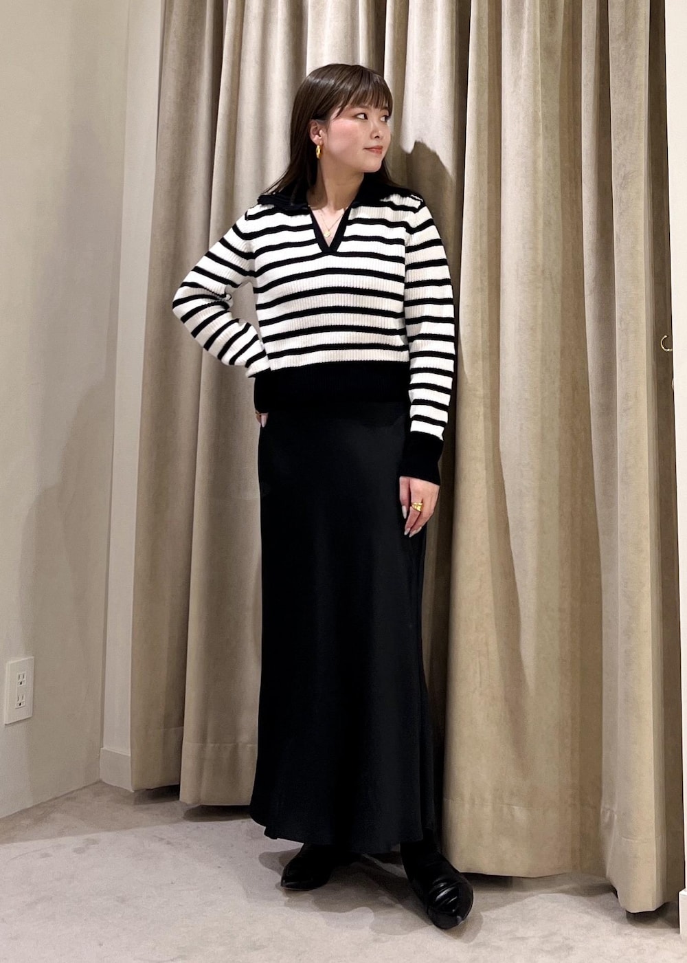 ブラック系のスカート、ベージュ系のトレンチコート、ホワイト系のニット/セーターを着用したレディースの冬コーディネートの2枚目の写真