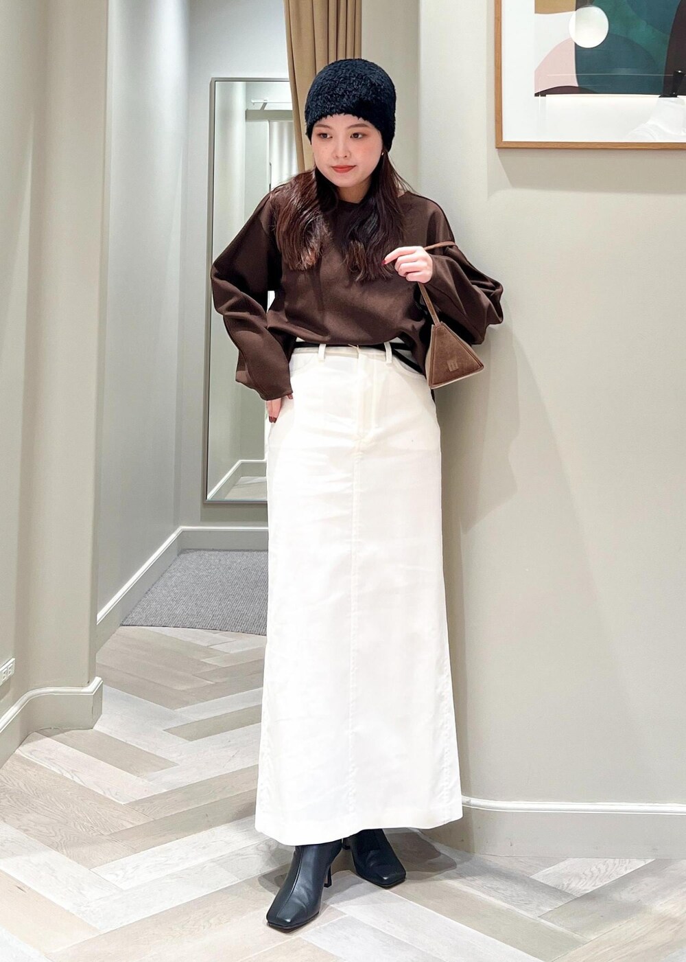 ブラック系のブーツ、ホワイト系のスカート、ブラウン系のTシャツ/カットソーを着用したレディースの秋コーディネートの2枚目の写真