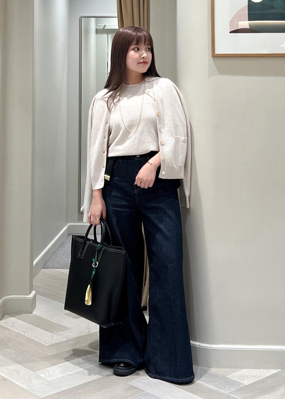 ベージュ系のカーディガン/ボレロ、ベージュ系のニット/セーター、ブルー系のデニムパンツを着用したレディースの秋コーディネートの2枚目の写真