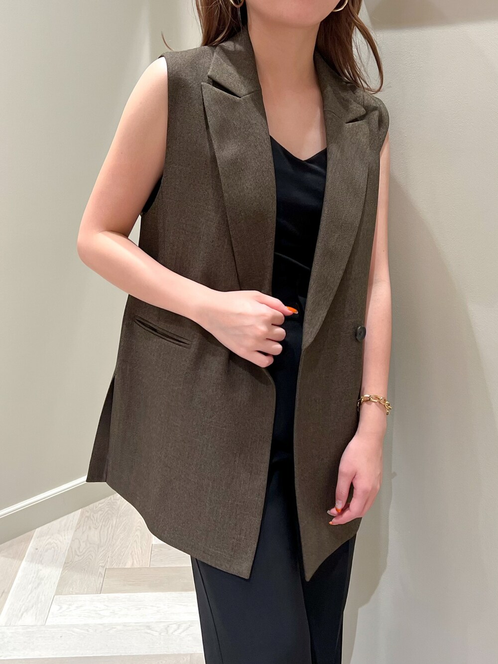 ブラウン系のベスト、レッド系のハンドバッグ、ブラック系のその他パンツを着用したレディースの夏コーディネートの2枚目の写真