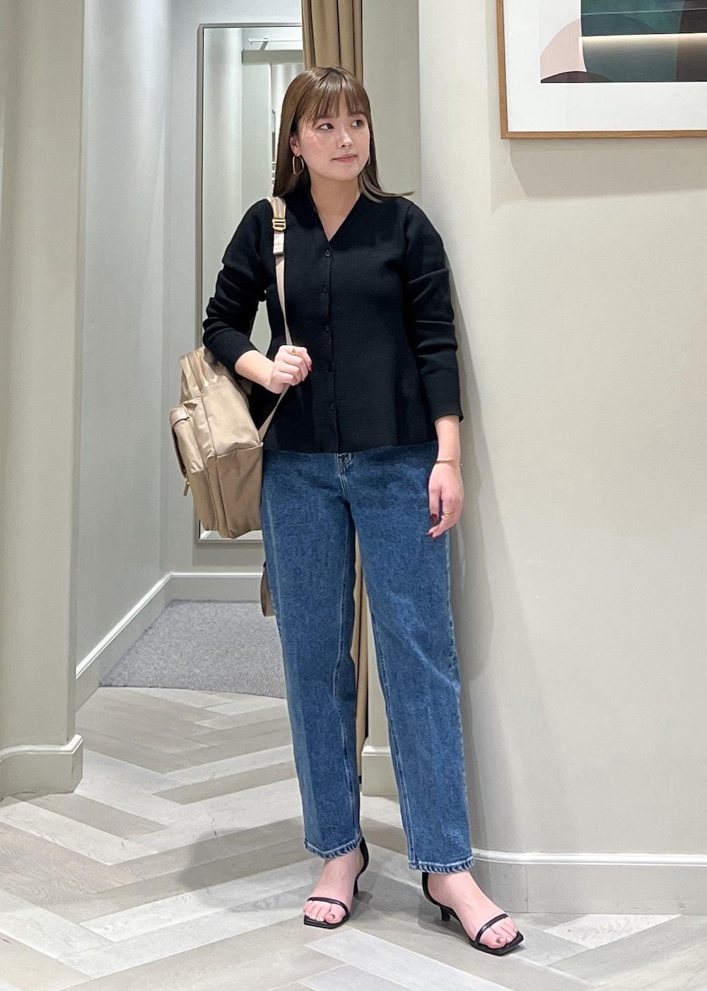 ブラック系のニット/セーター、ベージュ系のバックパック/リュック、ブルー系のデニムパンツを着用したレディースの冬コーディネートの3枚目の写真