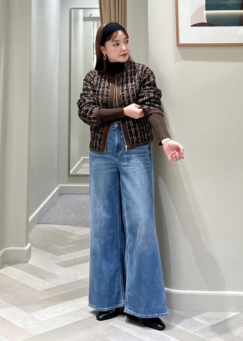 ブルー系のデニムパンツ、ブラック系のブーツ、ブラウン系のニット/セーターを着用したレディースの秋コーディネートの3枚目の写真