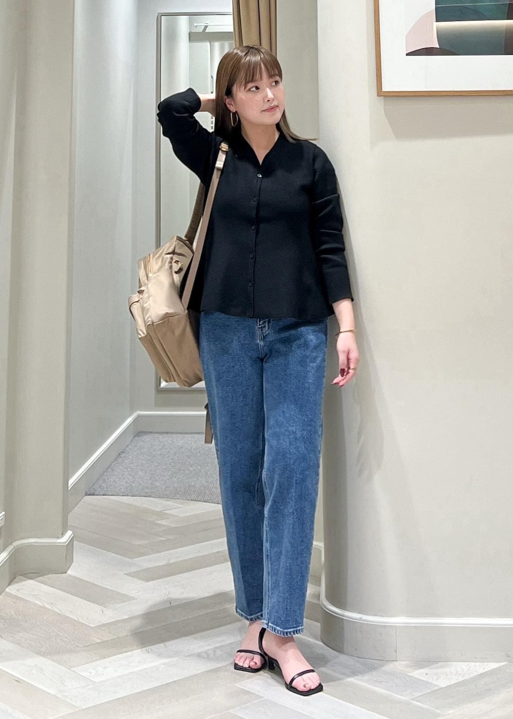 ブラック系のニット/セーター、ベージュ系のバックパック/リュック、ブルー系のデニムパンツを着用したレディースの冬コーディネートの2枚目の写真