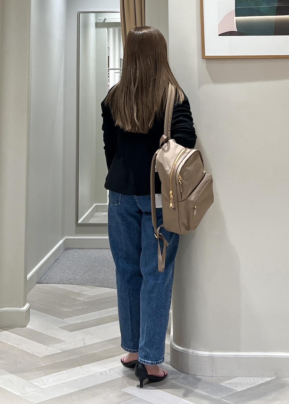 ブラック系のニット/セーター、ベージュ系のバックパック/リュック、ブルー系のデニムパンツを着用したレディースの冬コーディネートの5枚目の写真