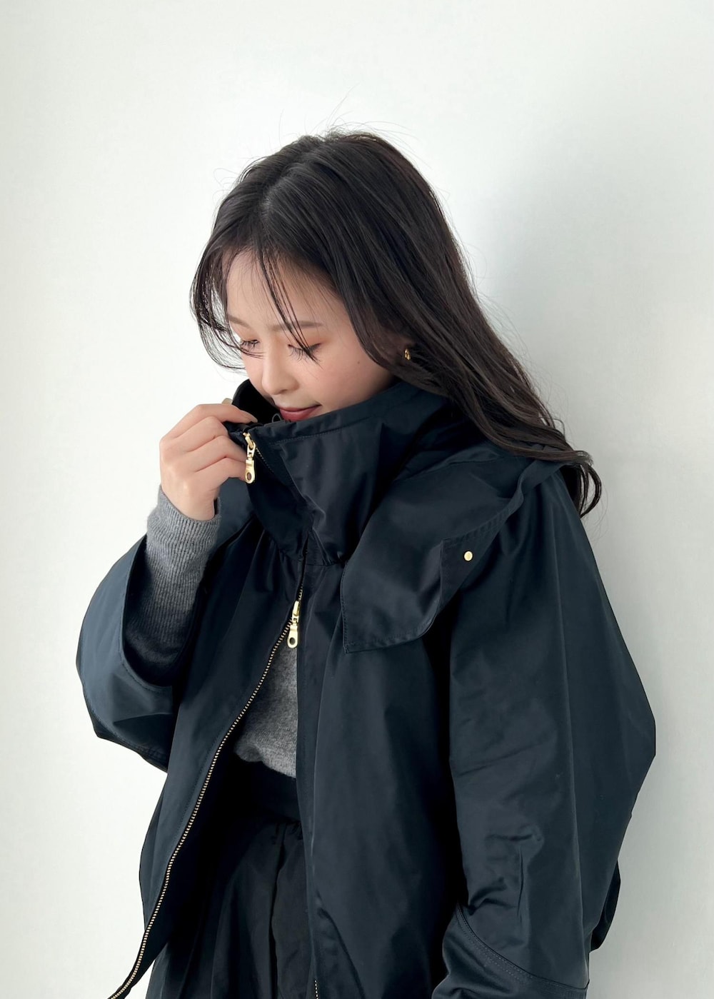 グレー系のニット/セーター、ブルー系のマウンテンパーカー、ブラック系のパンプスを着用したレディースの冬コーディネートの5枚目の写真