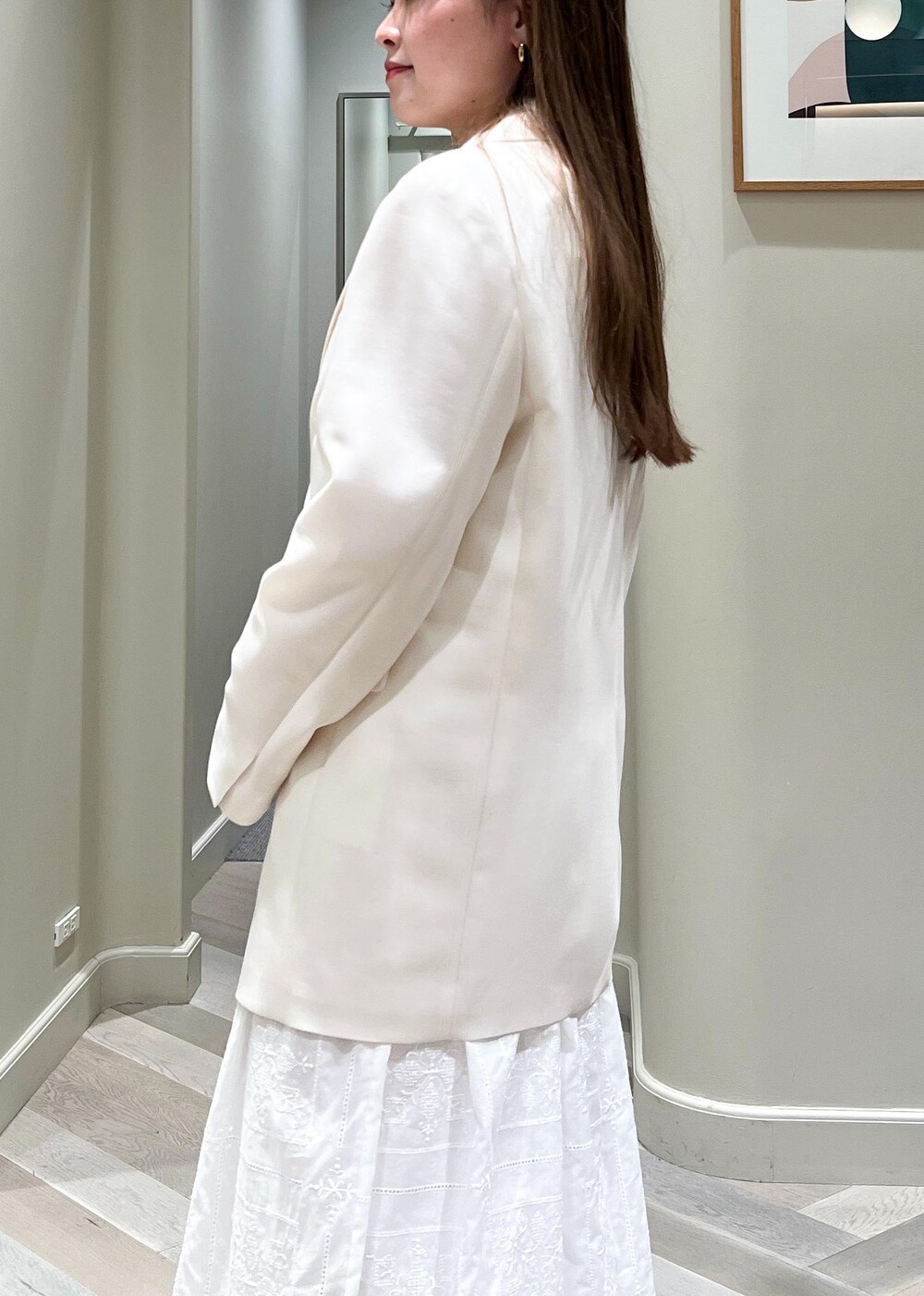 ホワイト系のテーラードジャケット、ブラック系のサンダル、ホワイト系のワンピースを着用したレディースの春コーディネートの7枚目の写真