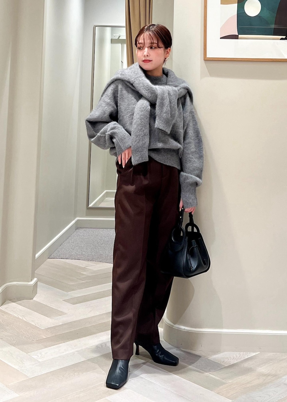 ブラック系のハンドバッグ、ブラック系のブーツ、グレー系のカーディガン/ボレロを着用したレディースの秋コーディネートの2枚目の写真