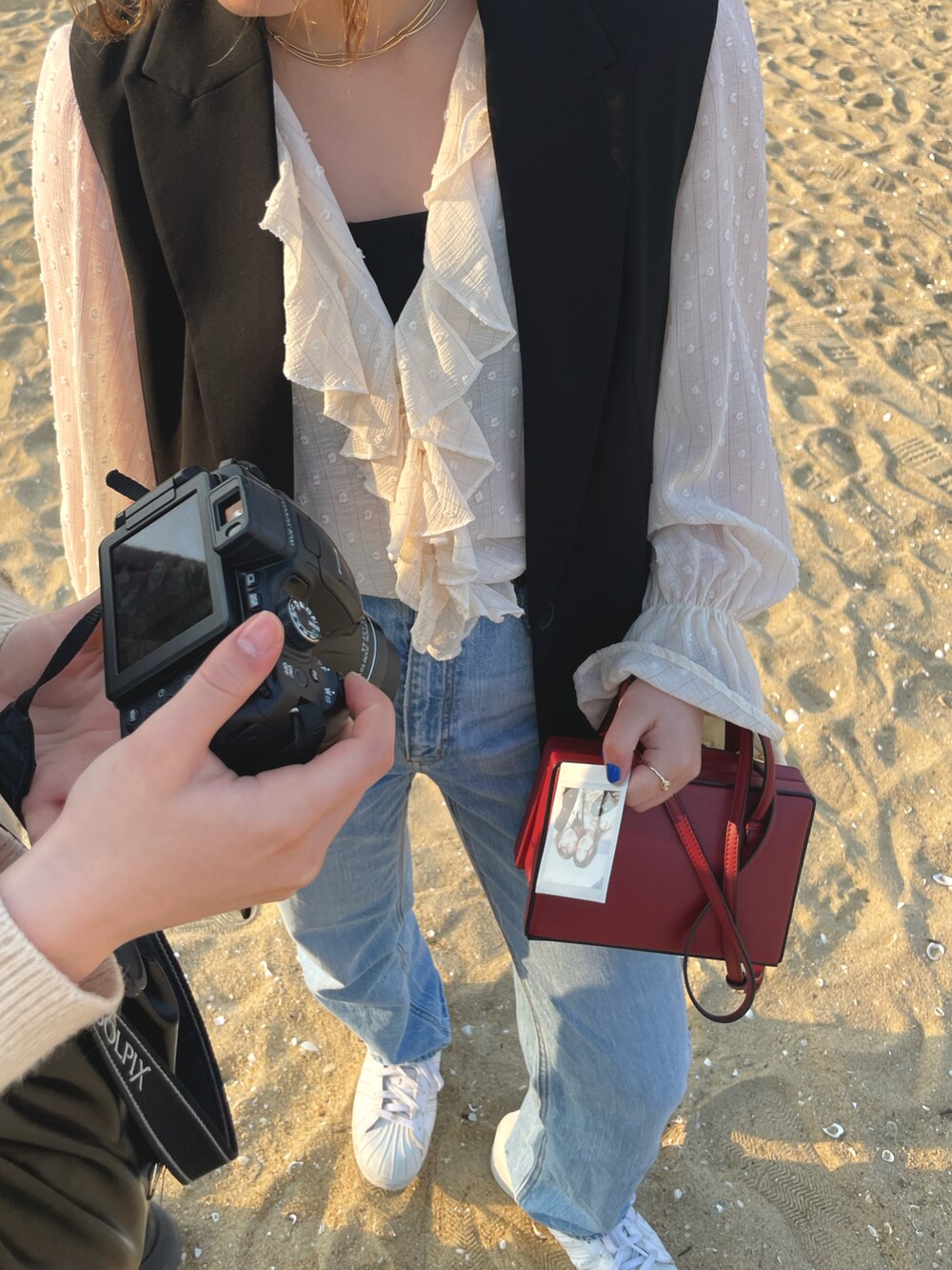 レッド系のショルダーバッグ、ブルー系のデニムパンツ、ホワイト系のシャツ/ブラウスを着用したレディースの春コーディネートの2枚目の写真