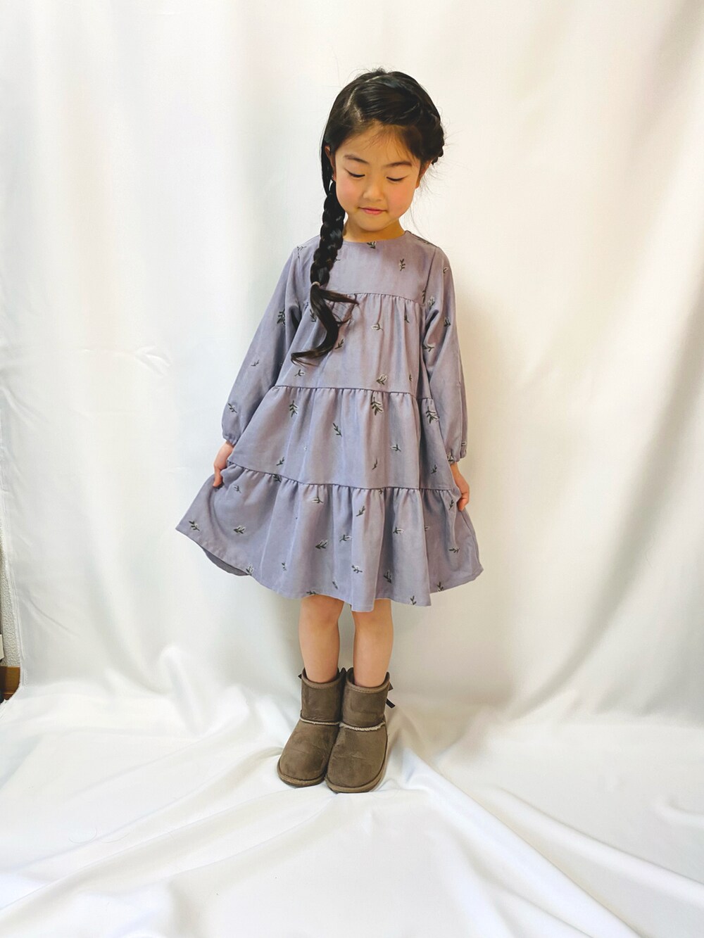 パープル系のワンピース、ブラウン系のブーツを着用したキッズの冬コーディネートの2枚目の写真