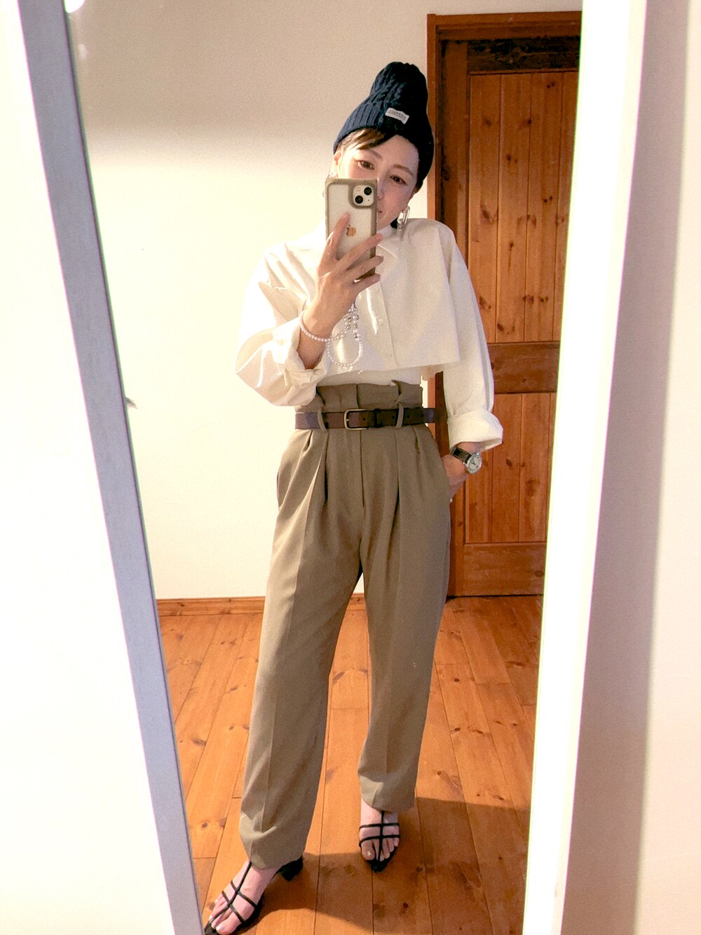 ベージュ系のスラックス、ブラック系のサンダル、ホワイト系のシャツ/ブラウスを着用したレディースの夏コーディネートの2枚目の写真