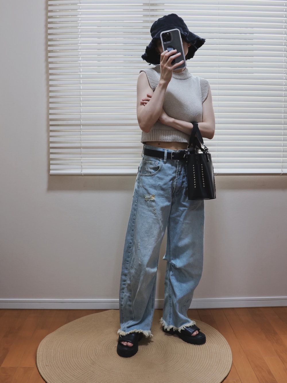 ベージュ系のニット/セーター、ブラック系のトートバッグ、ブルー系のデニムパンツを着用したレディースの夏コーディネートの2枚目の写真