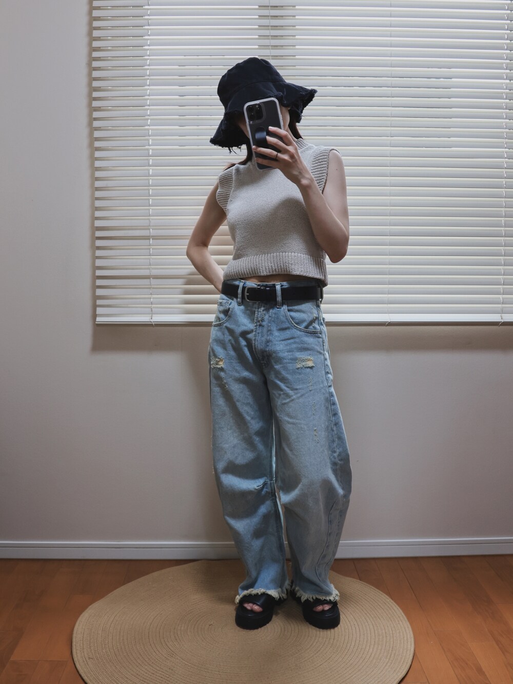 ベージュ系のニット/セーター、ブラック系のトートバッグ、ブルー系のデニムパンツを着用したレディースの夏コーディネートの3枚目の写真