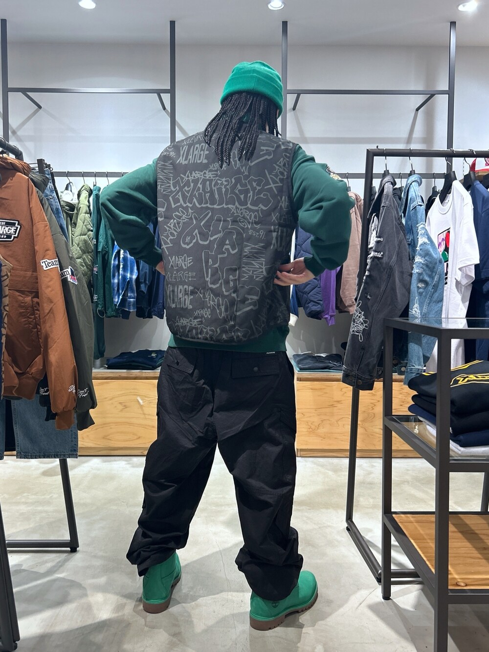 ブラック系のベスト、ブラック系のカーゴパンツ、グリーン系のスウェットを着用したメンズの秋コーディネートの2枚目の写真