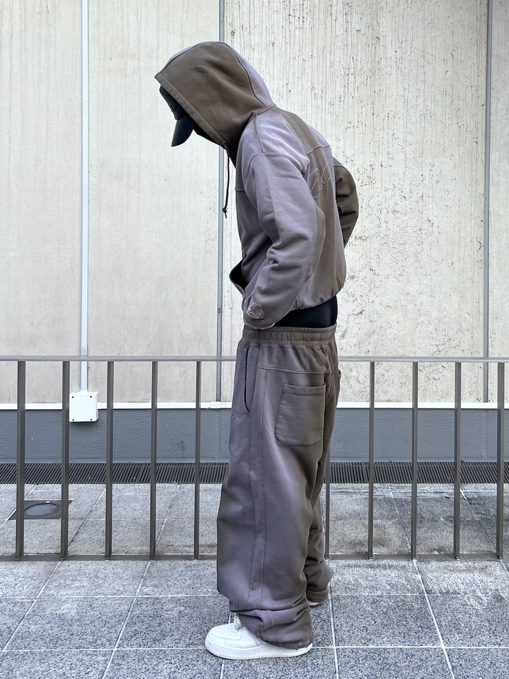 ブラウン系のパーカー、ブラウン系のスウェットパンツ、ブラック系のキャップを着用したメンズの冬コーディネートの4枚目の写真