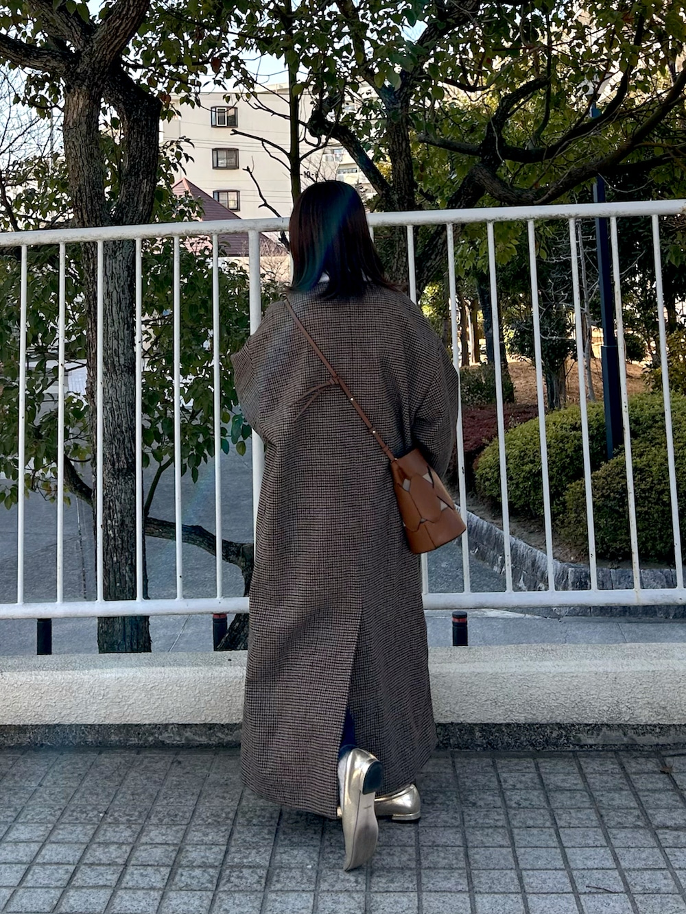 ブラック系のデニムパンツ、ホワイト系のその他トップス、ブラウン系のノーカラーコートを着用したレディースの春コーディネートの2枚目の写真