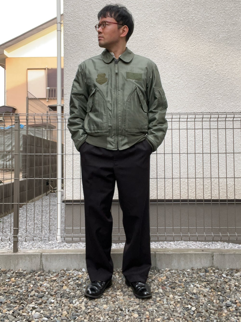 ホワイト系のシャツ/ブラウス、グリーン系のミリタリージャケット、ブラック系のスラックスを着用したメンズの冬コーディネートの2枚目の写真