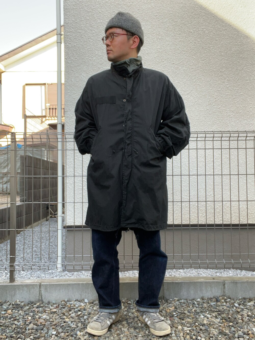 グリーン系のミリタリージャケット、ブルー系のデニムパンツ、グレー系のスニーカーを着用したメンズの冬コーディネートの2枚目の写真