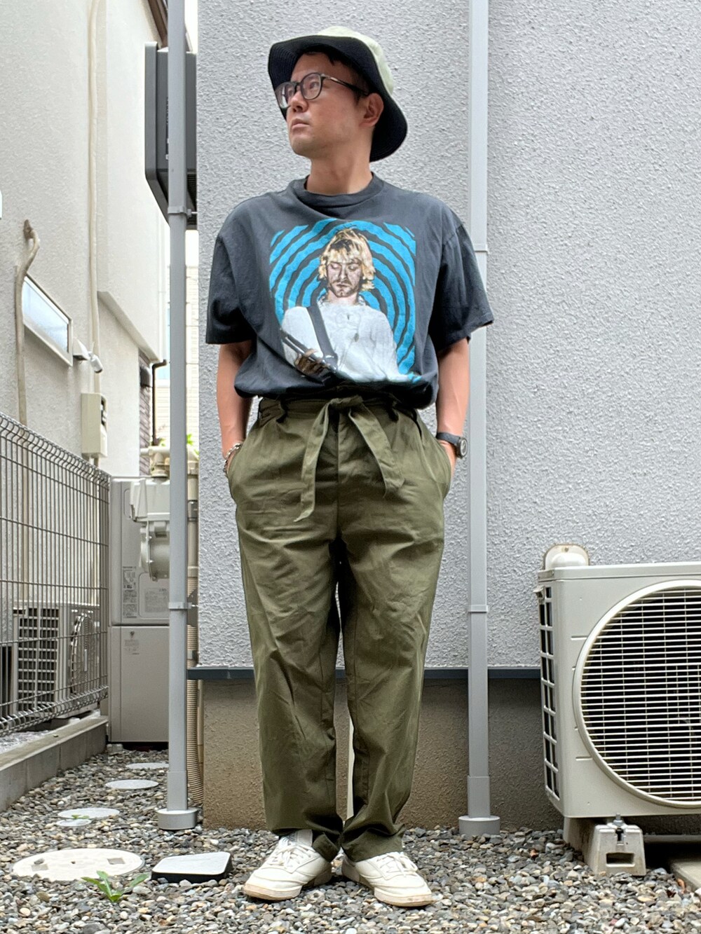 ブラック系のTシャツ/カットソー、レッド系のメッセンジャーバッグ、グリーン系のスラックスを着用したメンズの夏コーディネートの2枚目の写真