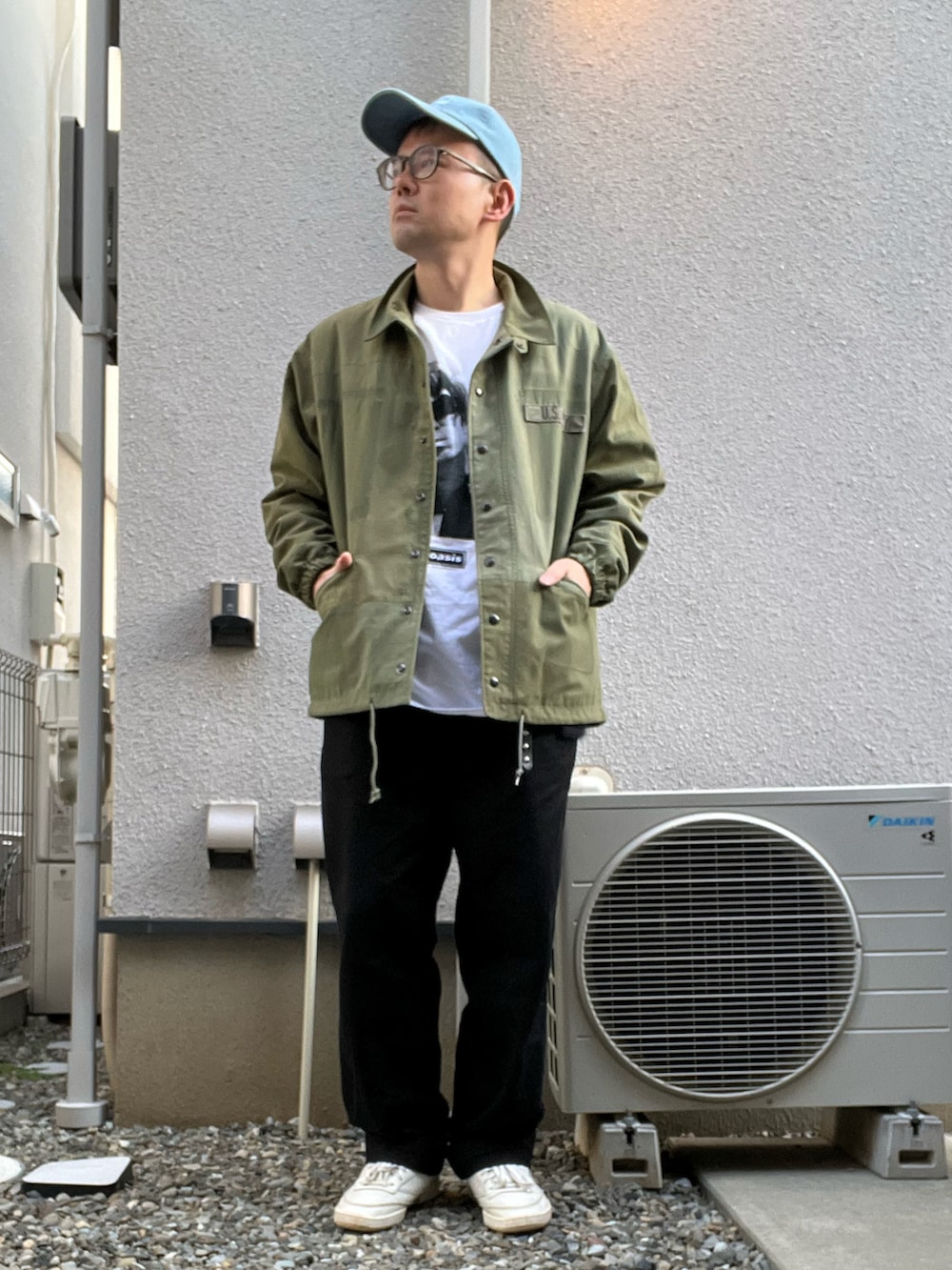 ホワイト系のTシャツ/カットソー、ブラック系のチノパンツ、ホワイト系のスニーカーを着用したメンズの春コーディネートの2枚目の写真