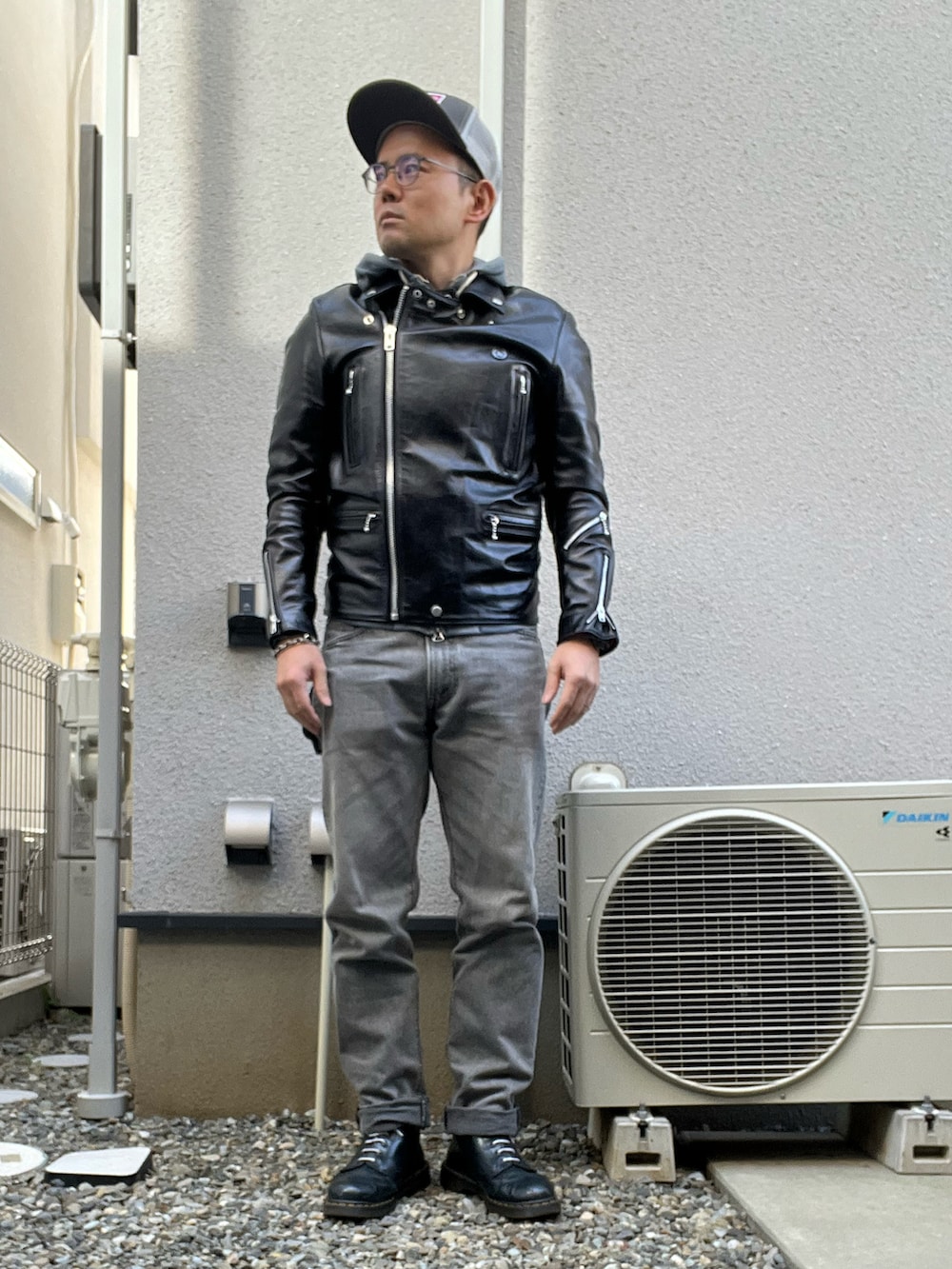 ブルー系のTシャツ/カットソー、ブラック系のライダースジャケット、グレー系のデニムパンツを着用したメンズの秋コーディネートの2枚目の写真