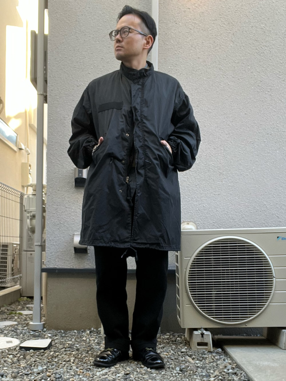 ブラック系のミリタリージャケット、ベージュ系のベスト、ブルー系のシャツ/ブラウスを着用したメンズの冬コーディネートの2枚目の写真