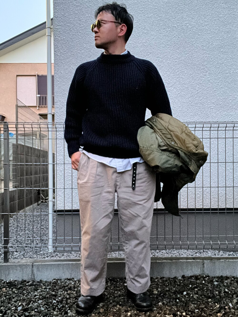 ブルー系のニット/セーター、ホワイト系のシャツ/ブラウス、ベージュ系のチノパンツを着用したメンズの冬コーディネートの2枚目の写真