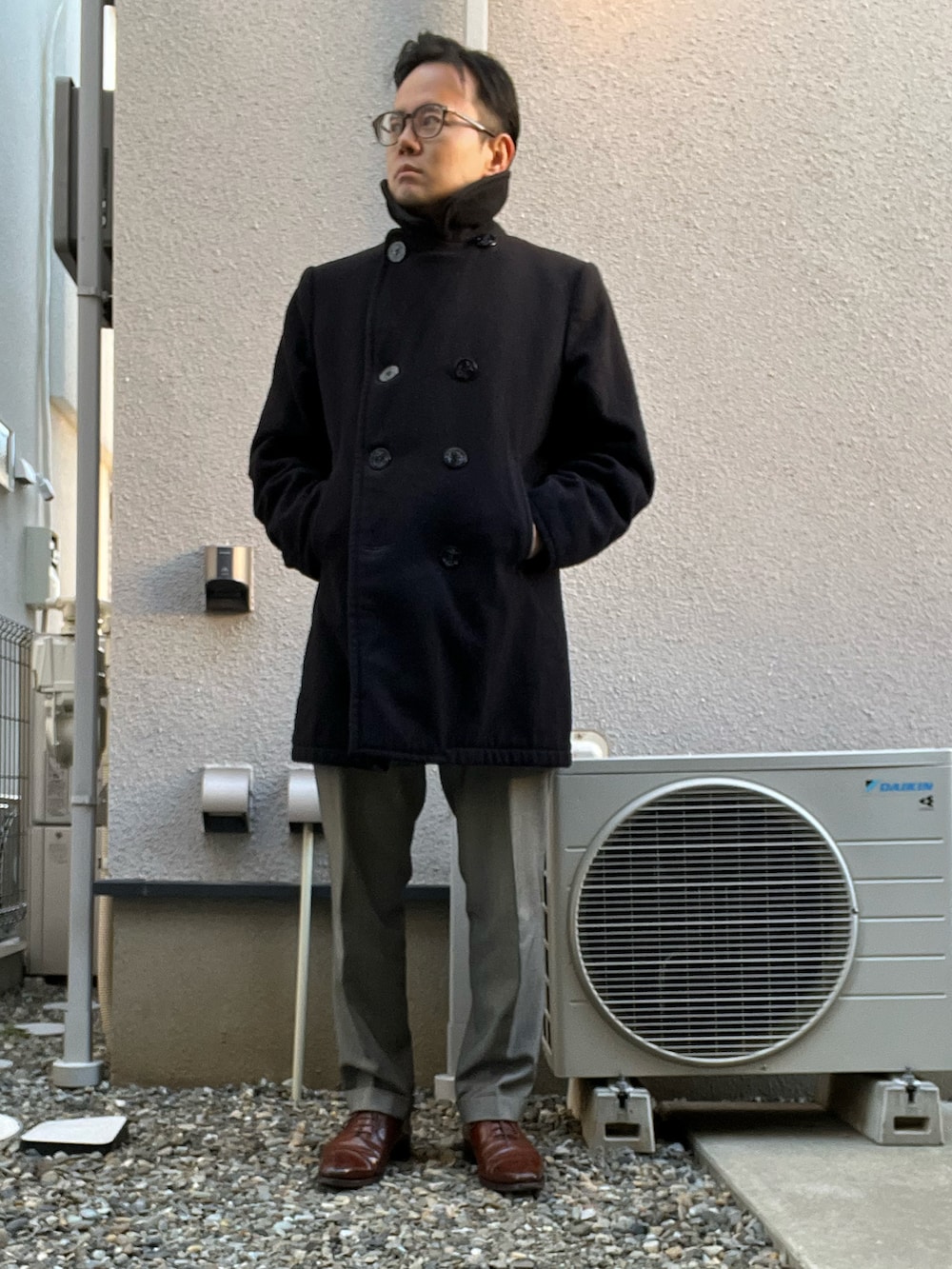 ブラック系のピーコート、グレー系のスーツセット、ブラウン系のドレスシューズを着用したメンズの冬コーディネートの3枚目の写真