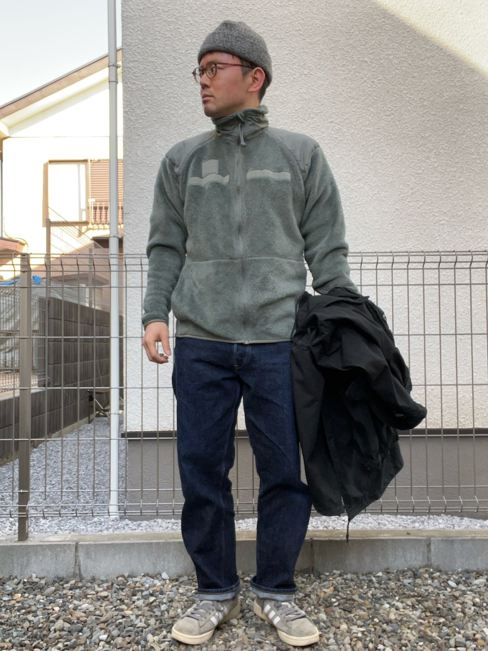 グリーン系のミリタリージャケット、ブルー系のデニムパンツ、グレー系のスニーカーを着用したメンズの冬コーディネートの3枚目の写真