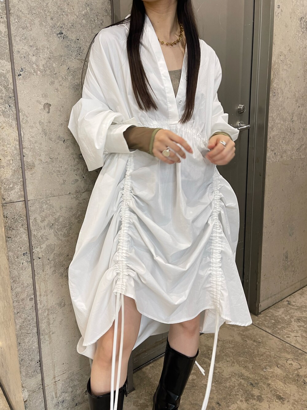 ホワイト系のシャツワンピース、ブラック系のブーツ、ベージュ系のトップスを着用したレディースの夏コーディネートの3枚目の写真