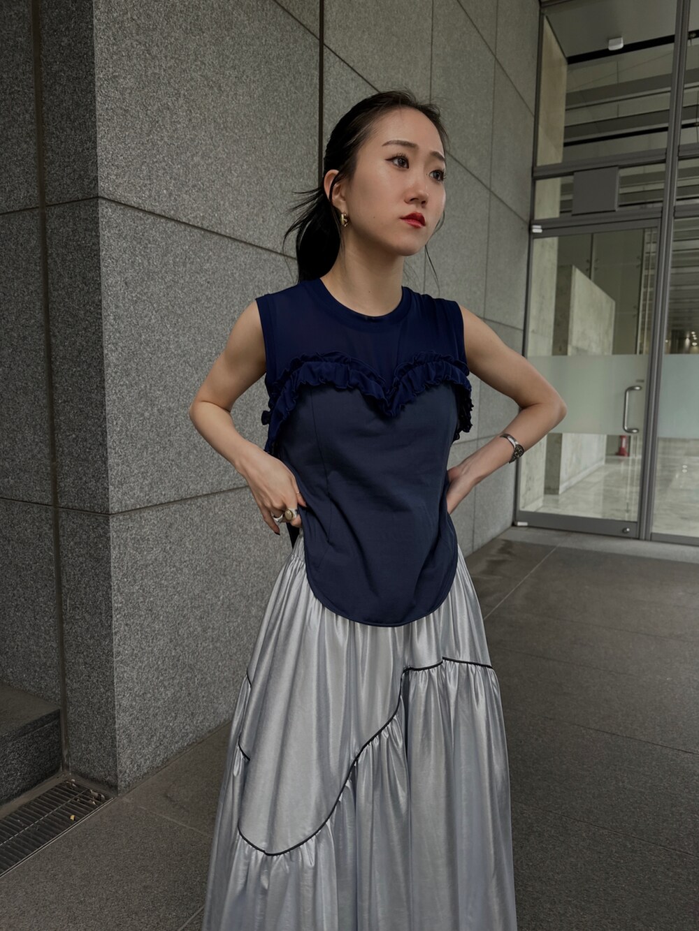 ブラック系のベスト、シルバー系のスカート、ブルー系のタンクトップを着用したレディースの夏コーディネートの4枚目の写真