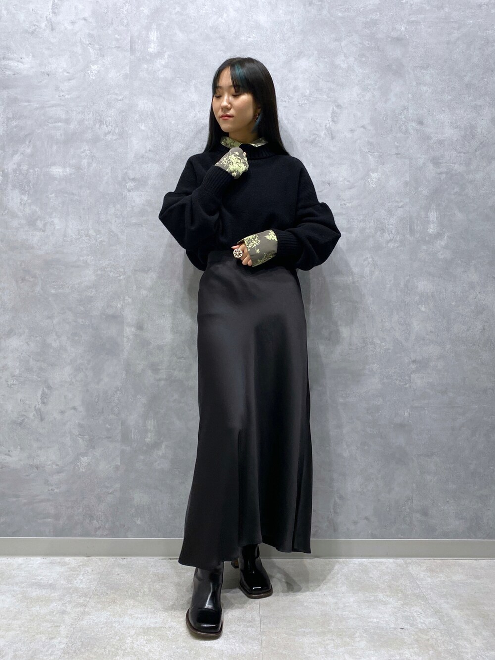 ブラック系のニット/セーター、ブラック系のスカート、グリーン系のシャツ/ブラウスを着用したレディースの秋コーディネートの2枚目の写真