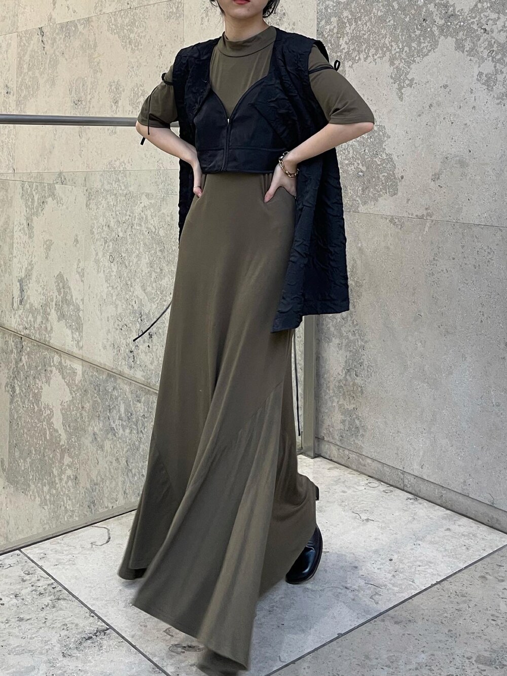 グリーン系のワンピース、ブラック系のベストを着用したレディースの秋コーディネートの4枚目の写真