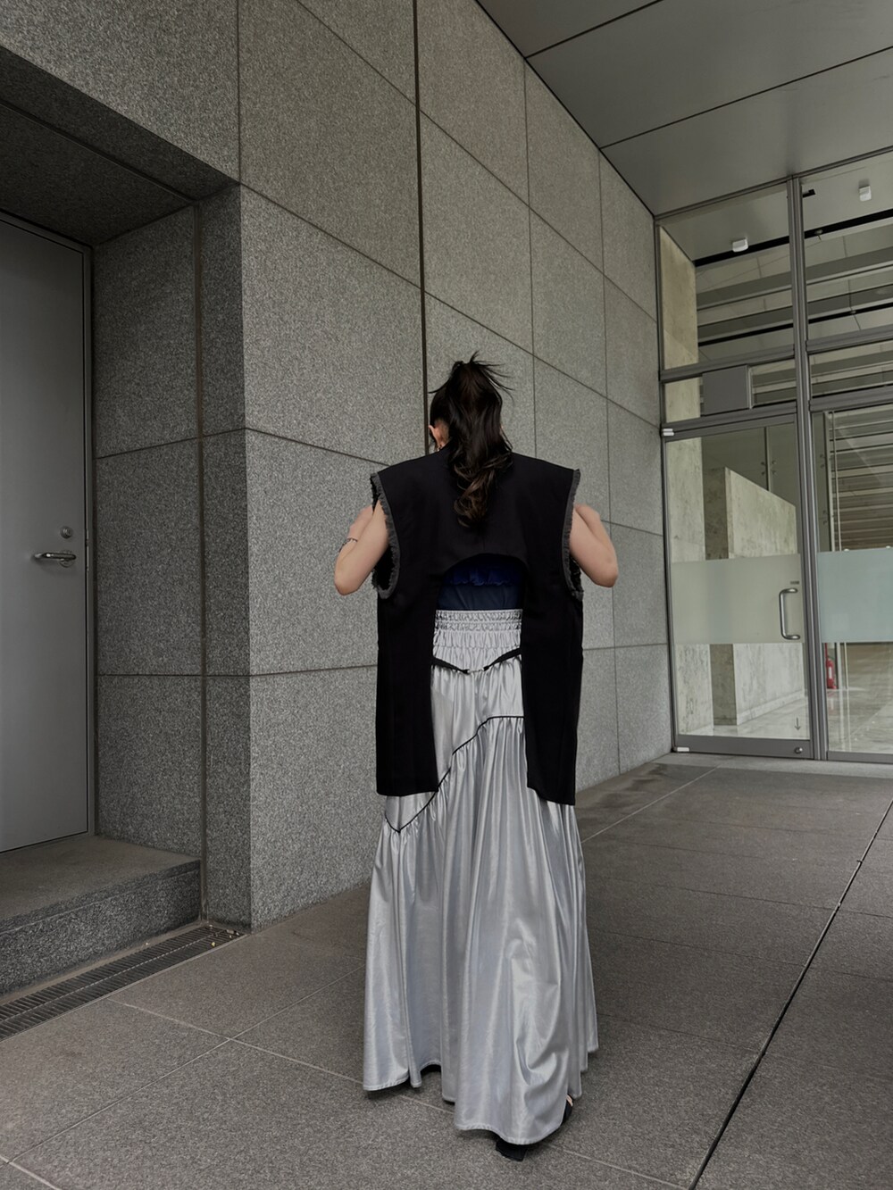 ブラック系のベスト、シルバー系のスカート、ブルー系のタンクトップを着用したレディースの夏コーディネートの5枚目の写真