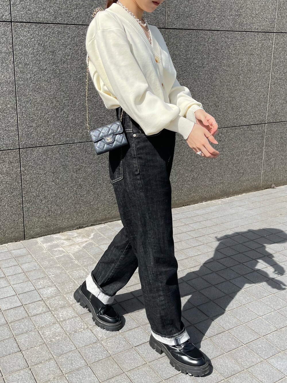 ホワイト系のカーディガン/ボレロ、ブラック系のデニムパンツ、ブラック系のブーツを着用したレディースの春コーディネートの2枚目の写真