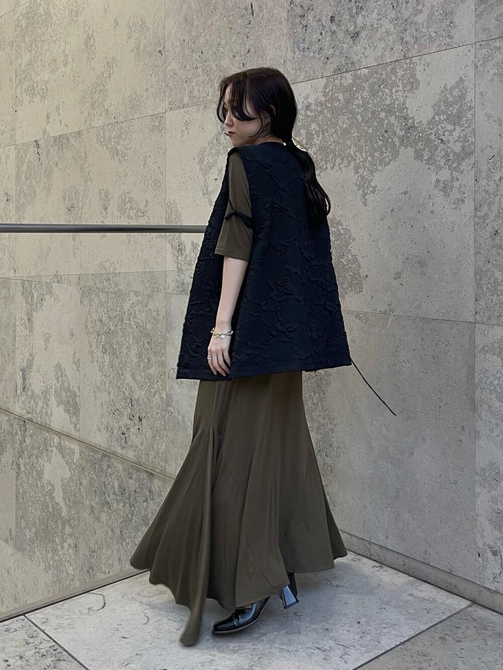 グリーン系のワンピース、ブラック系のベストを着用したレディースの秋コーディネートの2枚目の写真