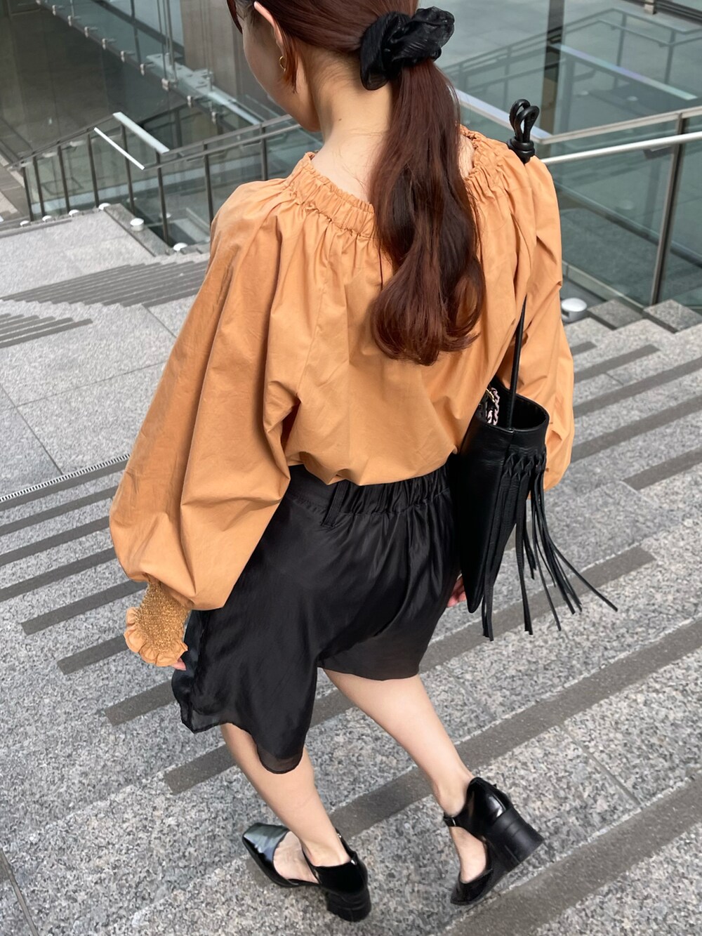 ブラック系のその他パンツ、オレンジ系のシャツ/ブラウス、ブラック系のパンプスを着用したレディースの春コーディネートの5枚目の写真