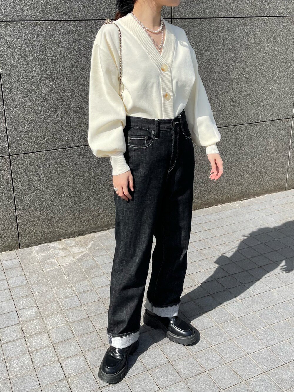 ホワイト系のカーディガン/ボレロ、ブラック系のデニムパンツ、ブラック系のブーツを着用したレディースの春コーディネートの5枚目の写真