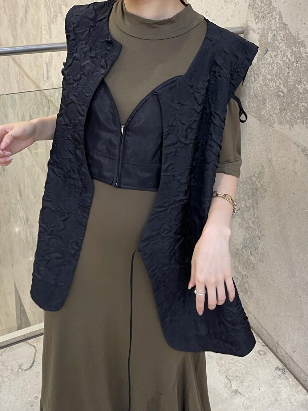 グリーン系のワンピース、ブラック系のベストを着用したレディースの秋コーディネートの3枚目の写真