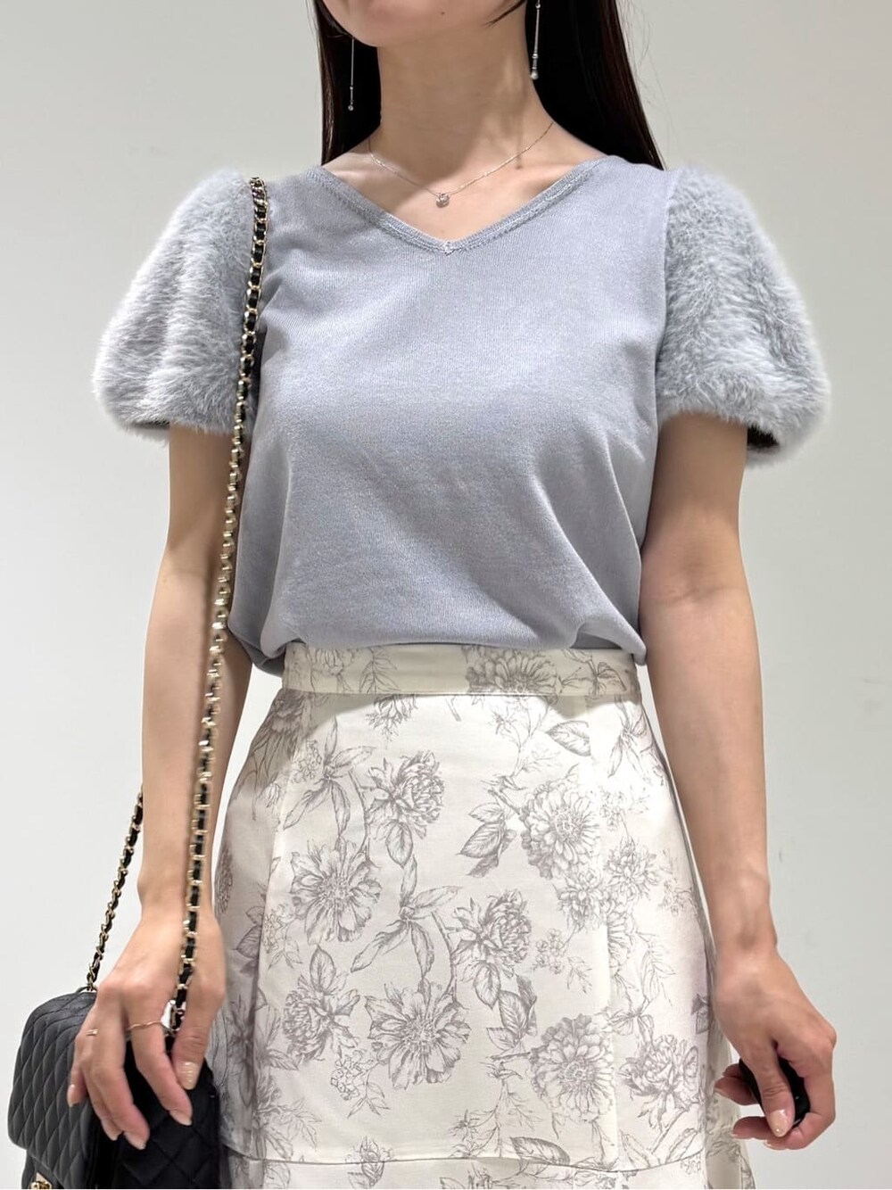 ブルー系のニット/セーター、グレー系のスカート、ブラック系のショルダーバッグを着用したレディースの秋コーディネートの2枚目の写真