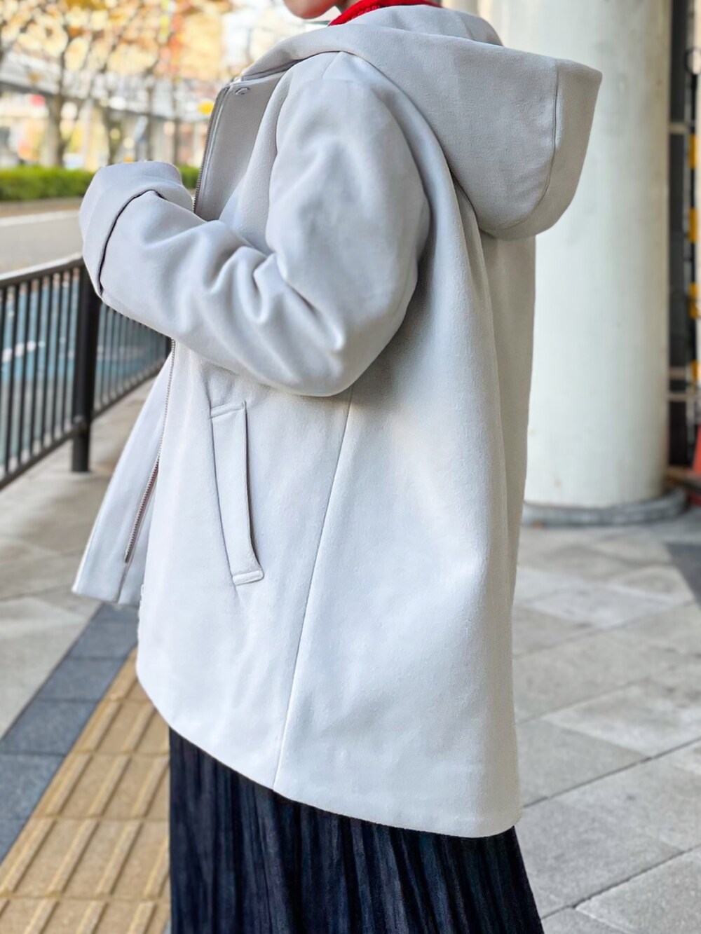 ベージュ系のその他アウター、レッド系のニット/セーター、ブルー系のスカートを着用したレディースの冬コーディネートの2枚目の写真