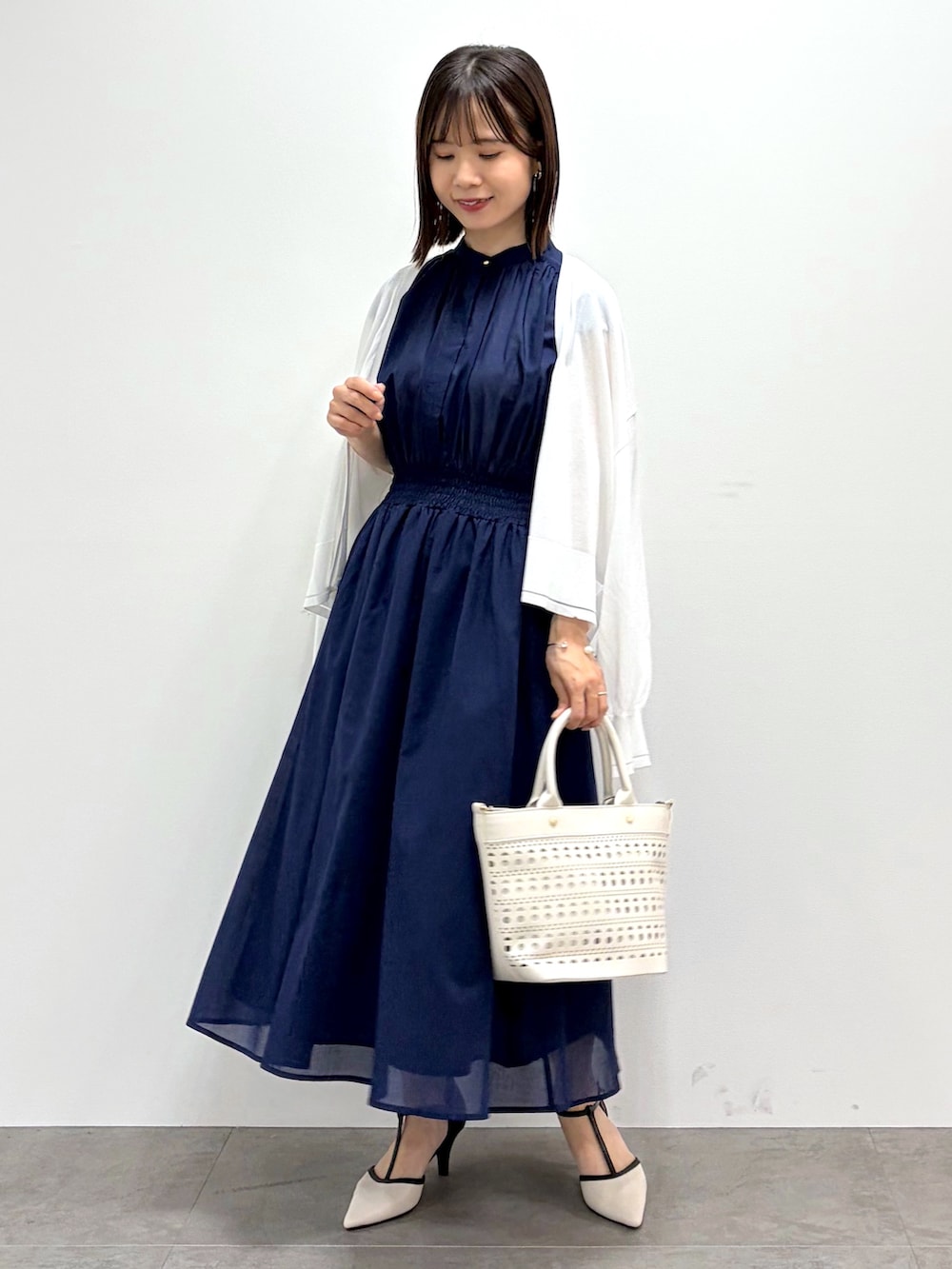 ブルー系のワンピース、ホワイト系のトートバッグ、ベージュ系のパンプスを着用したレディースの春コーディネートの2枚目の写真