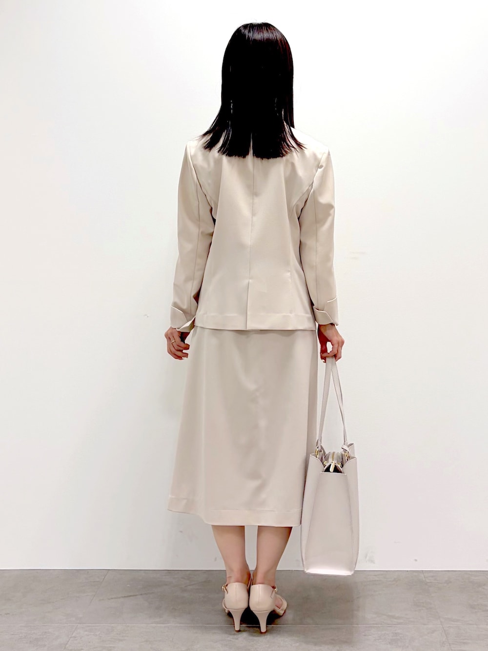 ベージュ系のスカート、ベージュ系のノーカラージャケット、ベージュ系のパンプスを着用したレディースの春コーディネートの6枚目の写真
