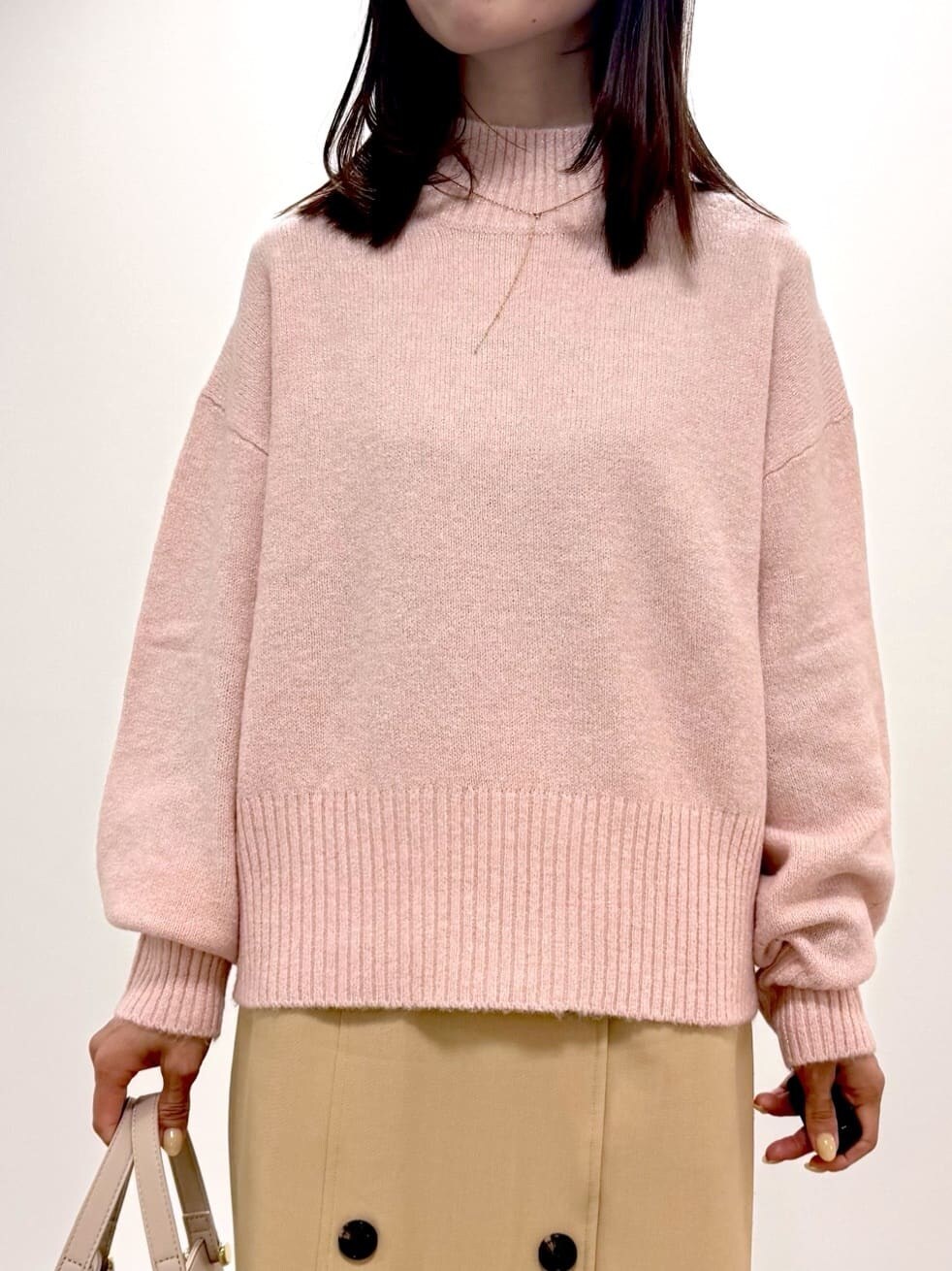 ピンク系のニット/セーター、ベージュ系のスカート、ベージュ系のボストンバッグを着用したレディースの冬コーディネートの2枚目の写真