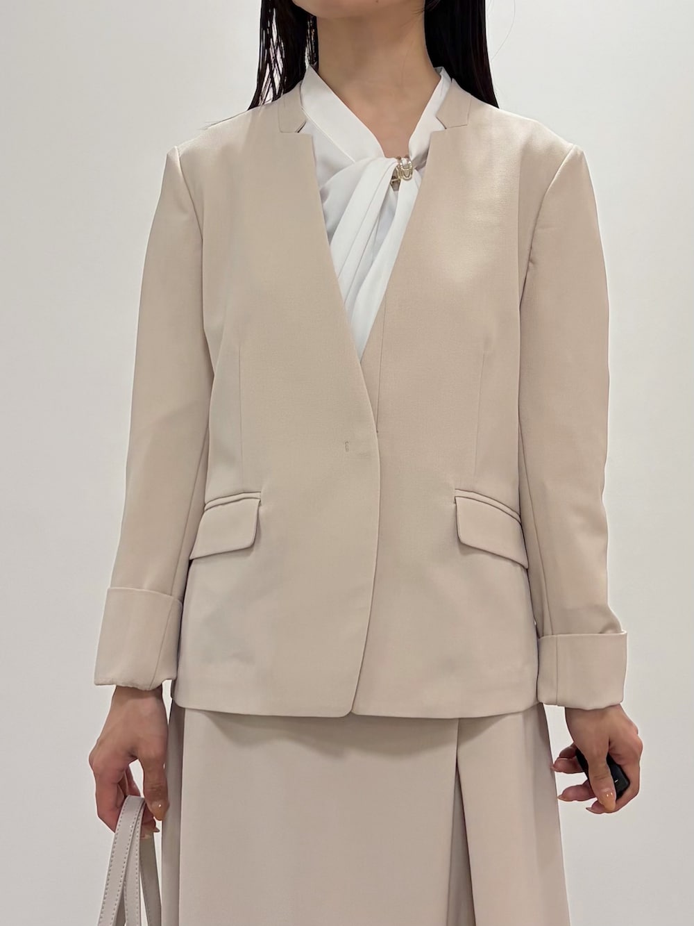 ベージュ系のスカート、ベージュ系のノーカラージャケット、ベージュ系のパンプスを着用したレディースの春コーディネートの4枚目の写真