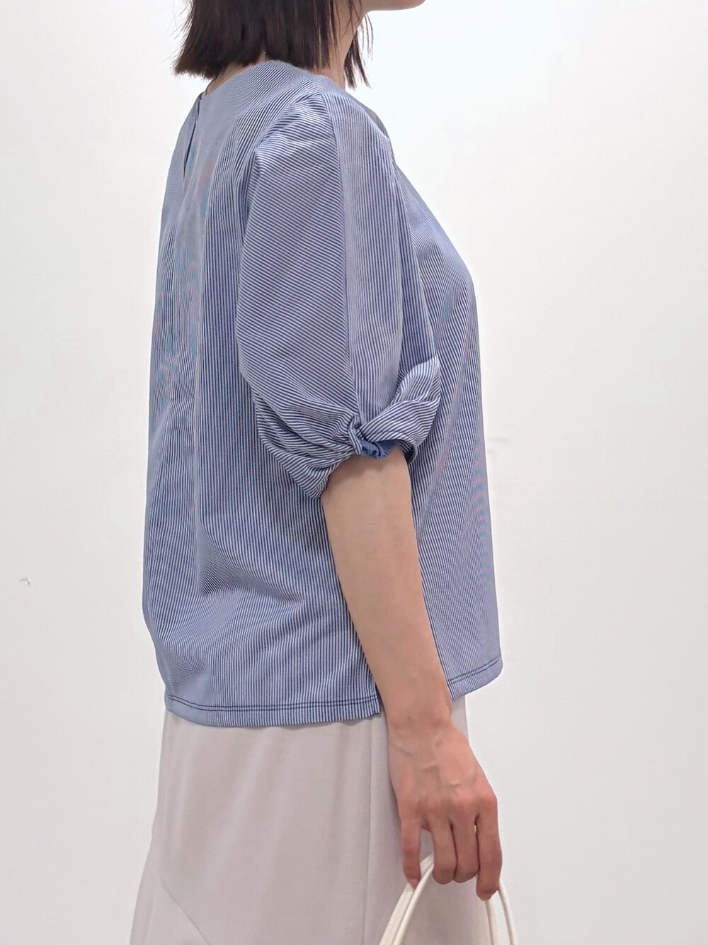 ブルー系のTシャツ/カットソー、ベージュ系のスカート、ホワイト系のトートバッグを着用したレディースの春コーディネートの10枚目の写真