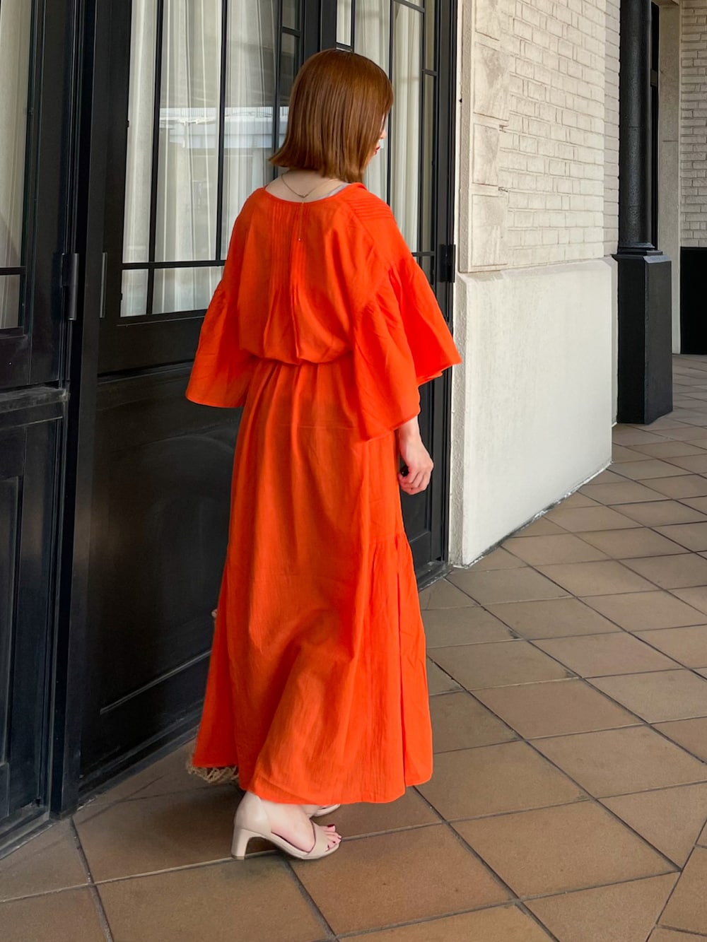 オレンジ系のワンピース、イエロー系のトートバッグを着用したレディースの夏コーディネートの2枚目の写真