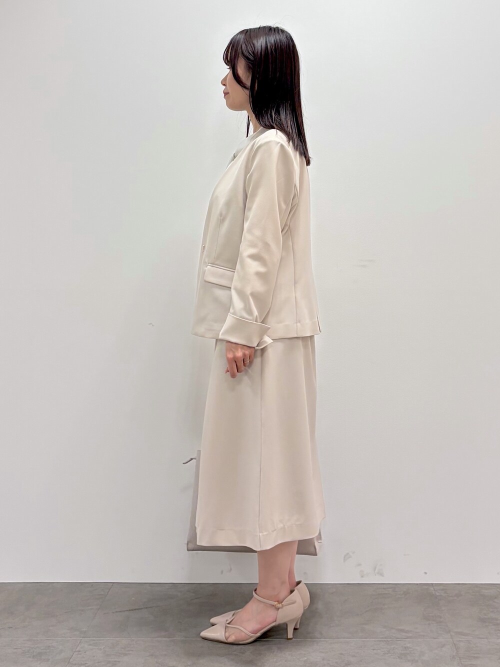 ベージュ系のスカート、ベージュ系のノーカラージャケット、ベージュ系のパンプスを着用したレディースの春コーディネートの5枚目の写真